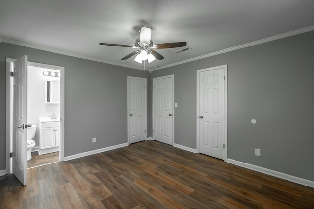 unfurnished bedroom with ensuite bathroom, sink, dark hardwood / wood-style flooring, multiple closets, and crown molding