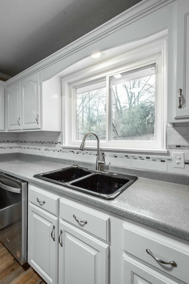 kitchen with sink, white cabinetry, backsplash, dark hardwood / wood-style floors, and stainless steel dishwasher