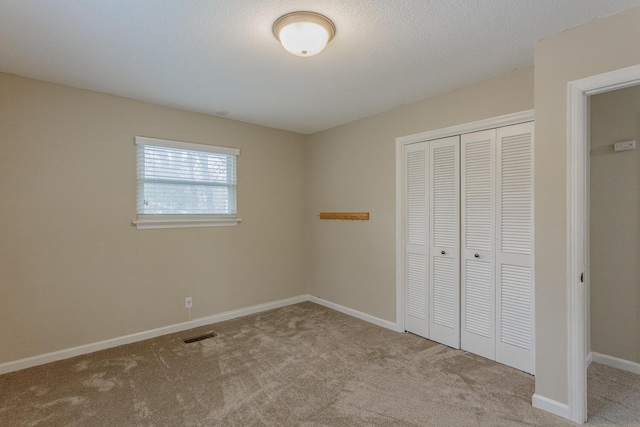 unfurnished bedroom featuring light carpet, a textured ceiling, and a closet