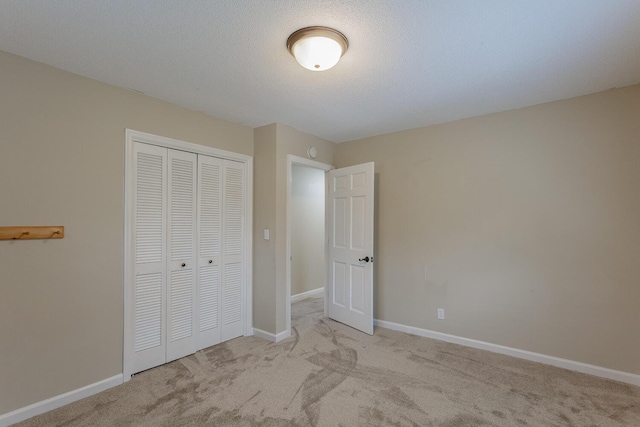 unfurnished bedroom with light colored carpet, a closet, and a textured ceiling