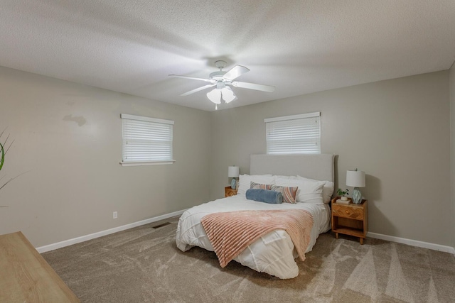 bedroom with ceiling fan, carpet, and a textured ceiling