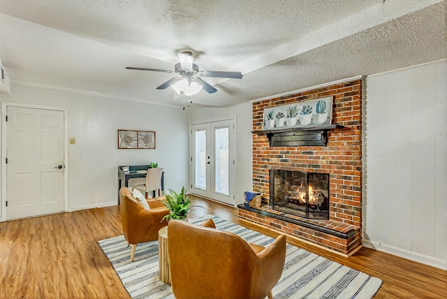 living room with hardwood / wood-style flooring, a textured ceiling, a brick fireplace, and french doors