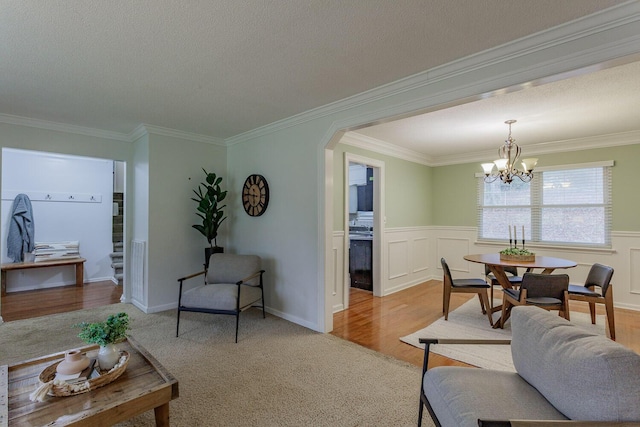 living room with a notable chandelier, light hardwood / wood-style flooring, ornamental molding, and a textured ceiling