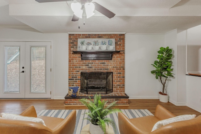 living room featuring french doors, wood-type flooring, a brick fireplace, a textured ceiling, and ornamental molding