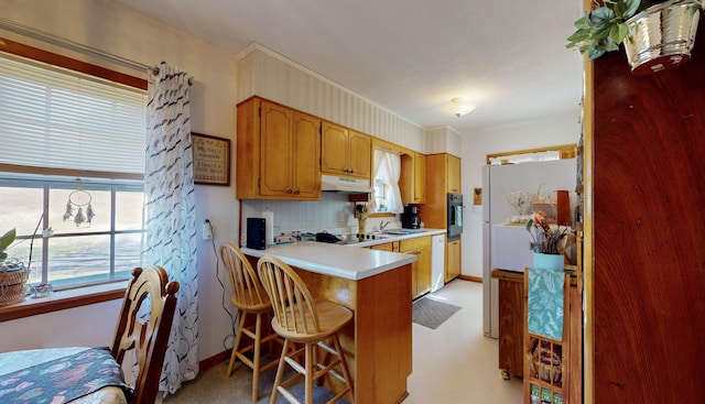 kitchen with sink, a breakfast bar area, black appliances, ornamental molding, and kitchen peninsula