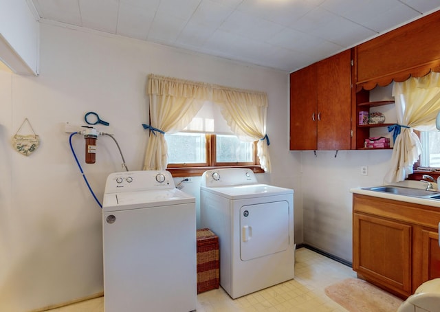 clothes washing area featuring sink, a wealth of natural light, cabinets, and washing machine and clothes dryer