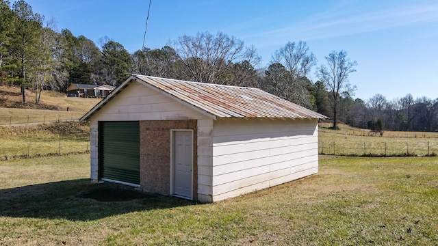 view of outdoor structure with a garage, a lawn, and a rural view