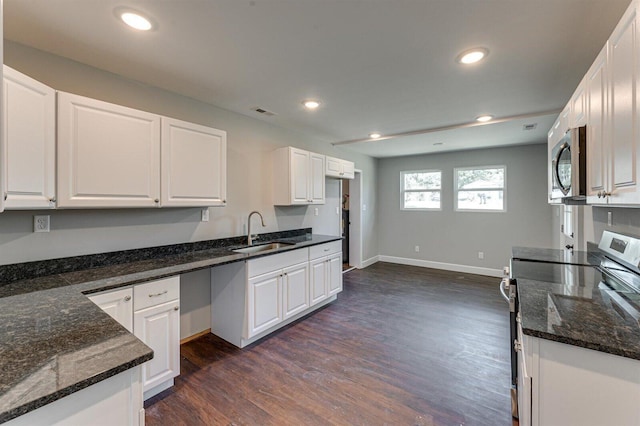 kitchen featuring white cabinetry, sink, dark stone counters, stainless steel appliances, and dark wood-type flooring