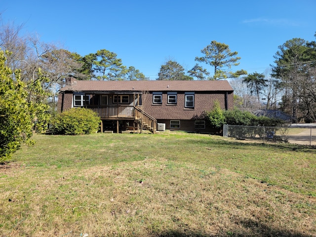 rear view of house with brick siding, a lawn, and fence