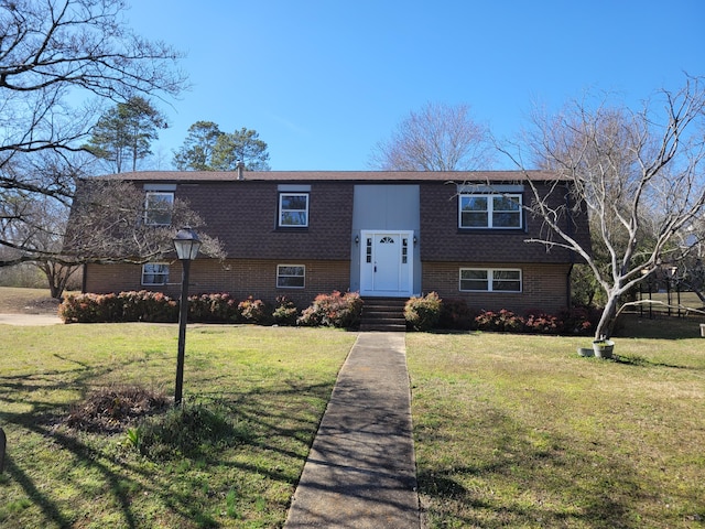 split foyer home with brick siding and a front lawn