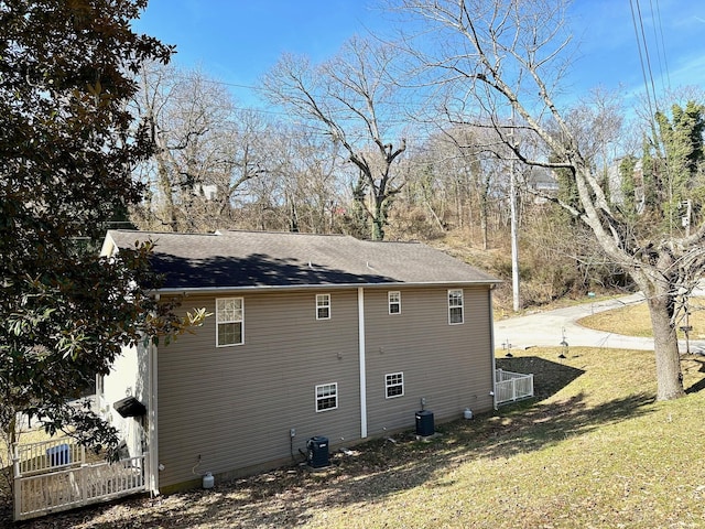 view of side of property with central AC and a lawn