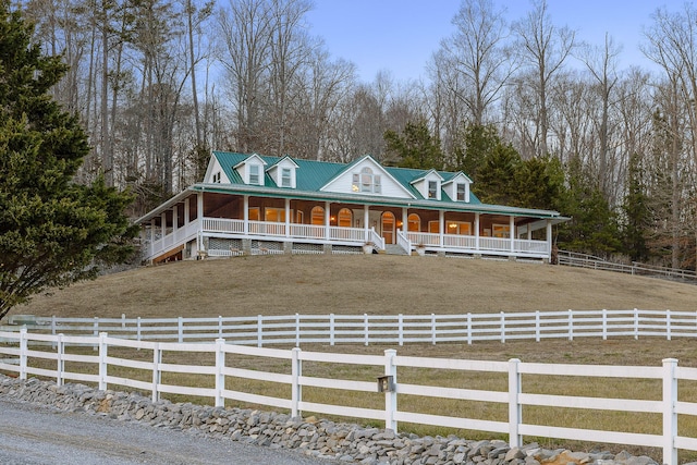 farmhouse featuring a rural view, a front yard, and covered porch