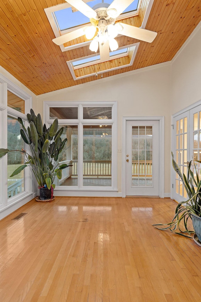 unfurnished sunroom featuring ceiling fan, wood ceiling, and vaulted ceiling with skylight