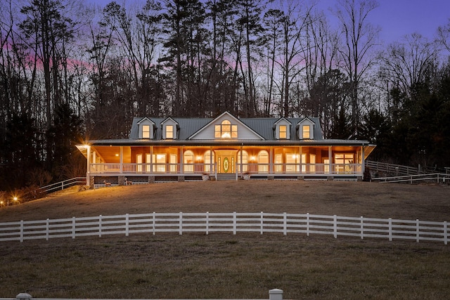 country-style home featuring covered porch and a lawn