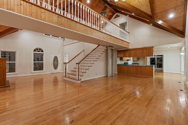 unfurnished living room with beamed ceiling, wood ceiling, high vaulted ceiling, and light hardwood / wood-style floors