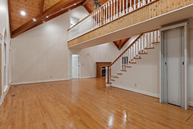 unfurnished living room featuring wood ceiling, light hardwood / wood-style flooring, ceiling fan, beam ceiling, and high vaulted ceiling