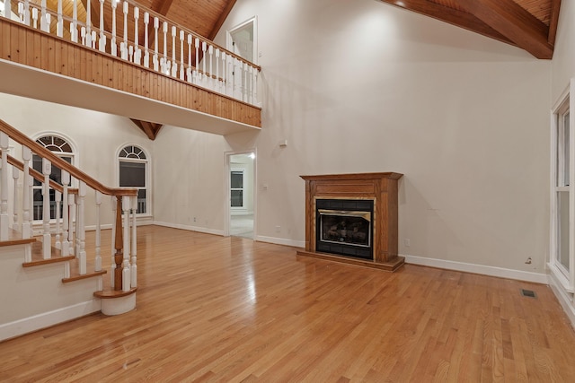 unfurnished living room featuring beam ceiling, high vaulted ceiling, wooden ceiling, and light wood-type flooring