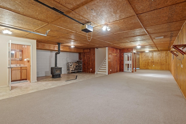 basement with wooden walls, carpet, and a wood stove