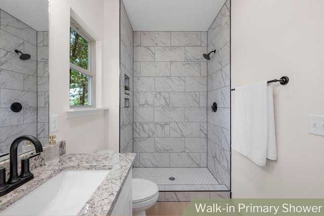 bathroom featuring vanity, tiled shower, a fireplace, and toilet