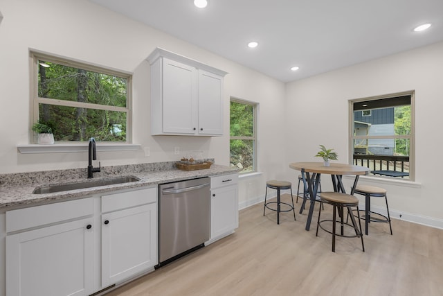 kitchen with sink, white cabinetry, light stone countertops, stainless steel dishwasher, and light wood-type flooring