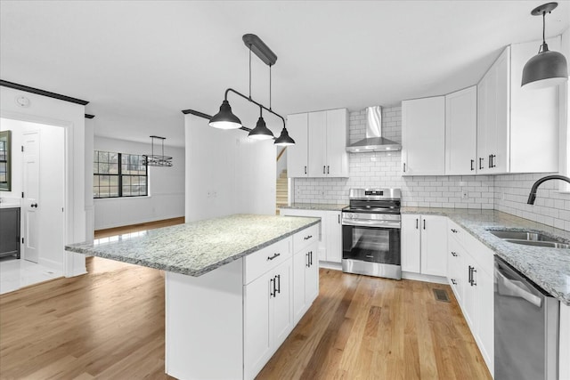 kitchen featuring white cabinets, appliances with stainless steel finishes, sink, and wall chimney range hood