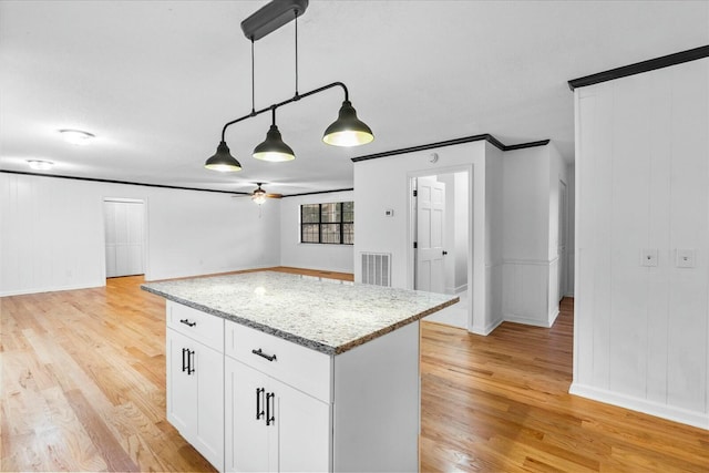 kitchen with pendant lighting, white cabinetry, light stone countertops, and light hardwood / wood-style flooring