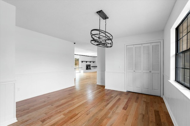 unfurnished dining area with an inviting chandelier and light hardwood / wood-style flooring