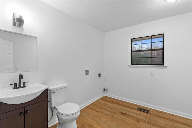 bathroom with vanity, toilet, hardwood / wood-style floors, and a textured ceiling