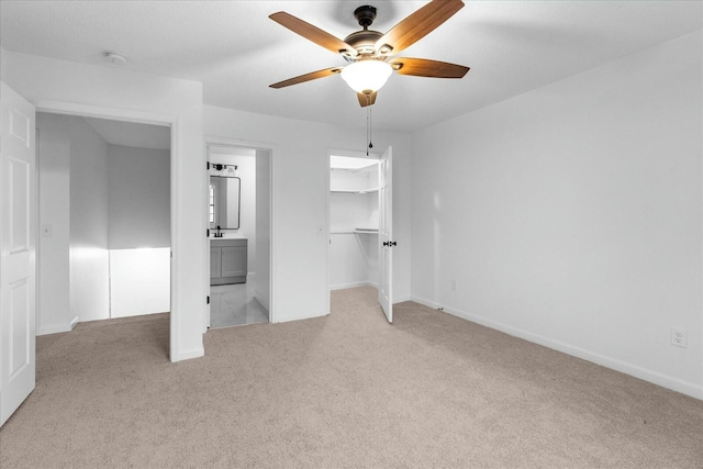 unfurnished bedroom featuring light colored carpet, a closet, ceiling fan, and ensuite bathroom