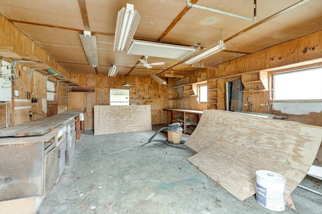 miscellaneous room featuring wooden walls, a workshop area, and a wealth of natural light