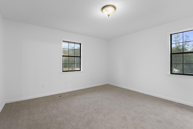 carpeted empty room featuring a textured ceiling