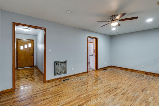 unfurnished room featuring ceiling fan, heating unit, and light wood-type flooring