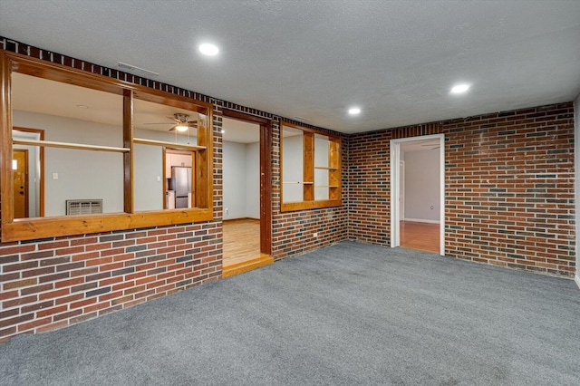 carpeted empty room with brick wall and a textured ceiling