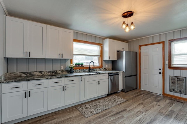 kitchen with pendant lighting, heating unit, sink, white cabinets, and stainless steel appliances