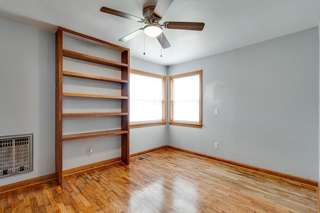 empty room featuring ceiling fan, heating unit, and light wood-type flooring