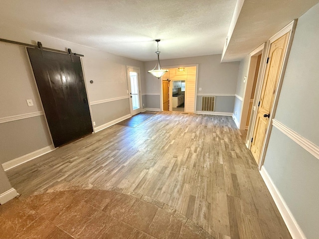 interior space with hardwood / wood-style flooring, a barn door, and a textured ceiling