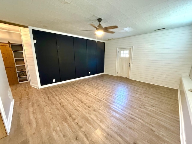 unfurnished room with ceiling fan, a barn door, and light wood-type flooring