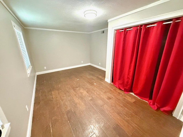 unfurnished room with hardwood / wood-style floors, ornamental molding, and a textured ceiling