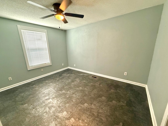 empty room with ceiling fan and a textured ceiling