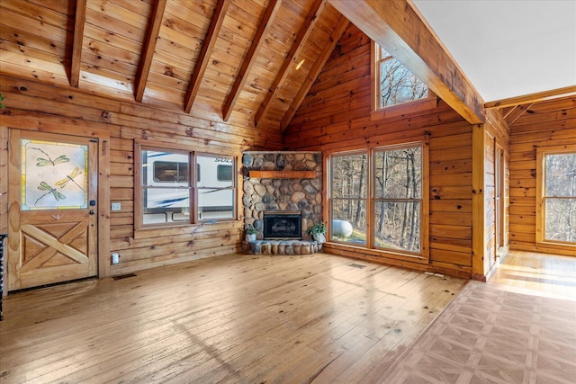 unfurnished living room with light hardwood / wood-style flooring, a fireplace, beam ceiling, and wooden walls