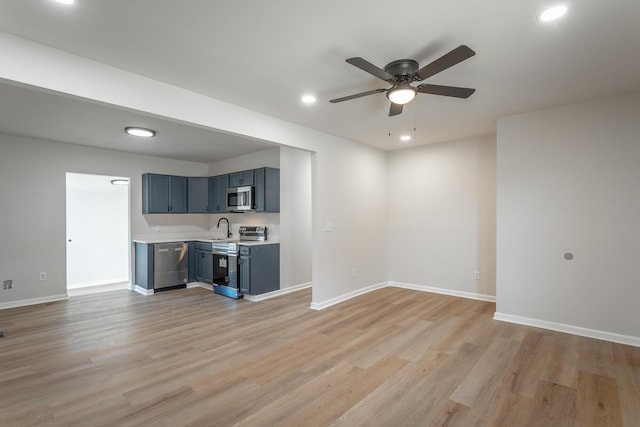 unfurnished living room with sink, ceiling fan, and light wood-type flooring