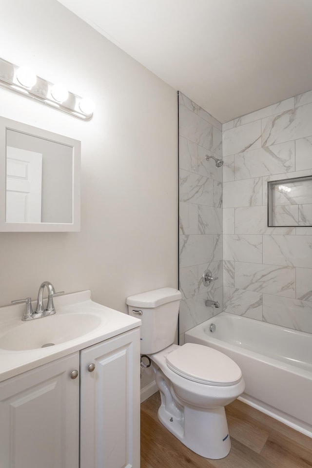 full bathroom with hardwood / wood-style flooring, vanity, toilet, and tiled shower / bath