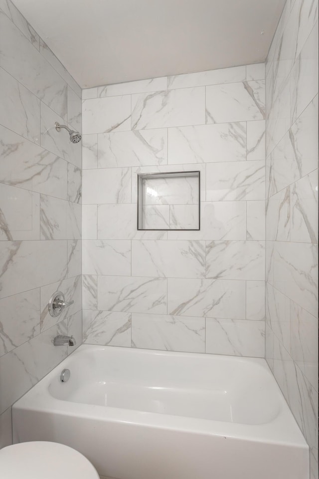 bathroom with tiled shower / bath combo and toilet