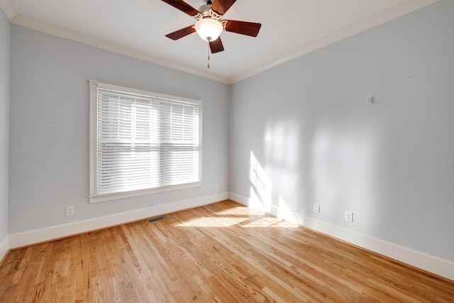 empty room featuring visible vents, ornamental molding, a ceiling fan, wood finished floors, and baseboards