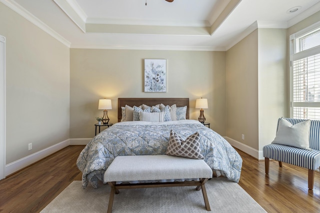 bedroom featuring a tray ceiling, wood finished floors, and baseboards