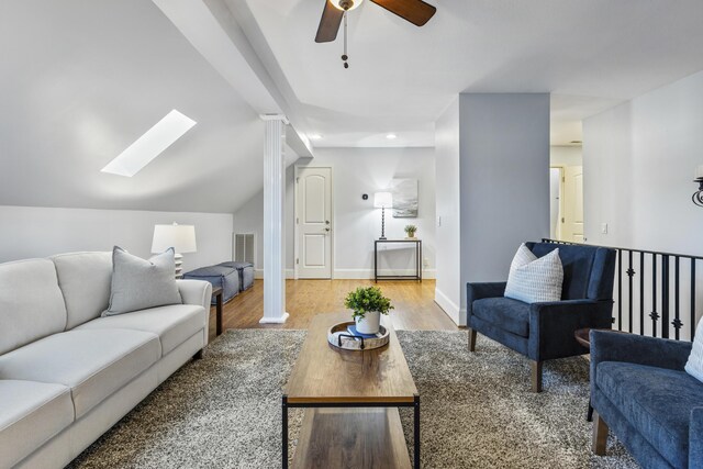 living area featuring a ceiling fan, baseboards, light wood finished floors, visible vents, and lofted ceiling with skylight
