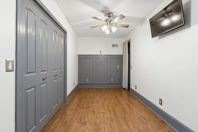 unfurnished bedroom featuring visible vents, baseboards, a closet, and wood finished floors
