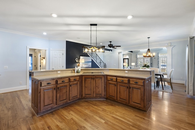kitchen featuring wood finished floors, brown cabinets, and ornamental molding