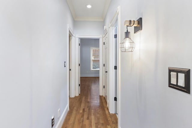 hallway featuring ornamental molding, baseboards, and wood finished floors