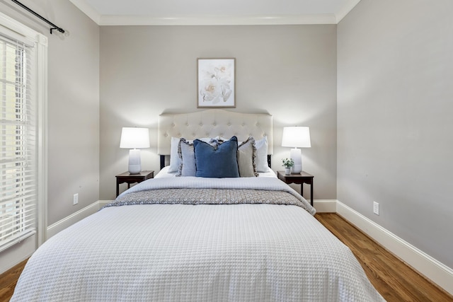 bedroom featuring crown molding, baseboards, and wood finished floors